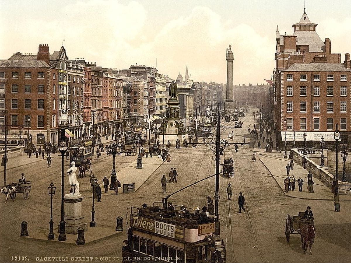 Vintage Image of OConnell Street or Sackville Street Dublin | Irish American Mom Historic Dublin street scene with Sackville Street and O'Connell Bridge: brick buildings, a central statue, horse-drawn carriages, and a double-decker tram in a busy plaza.