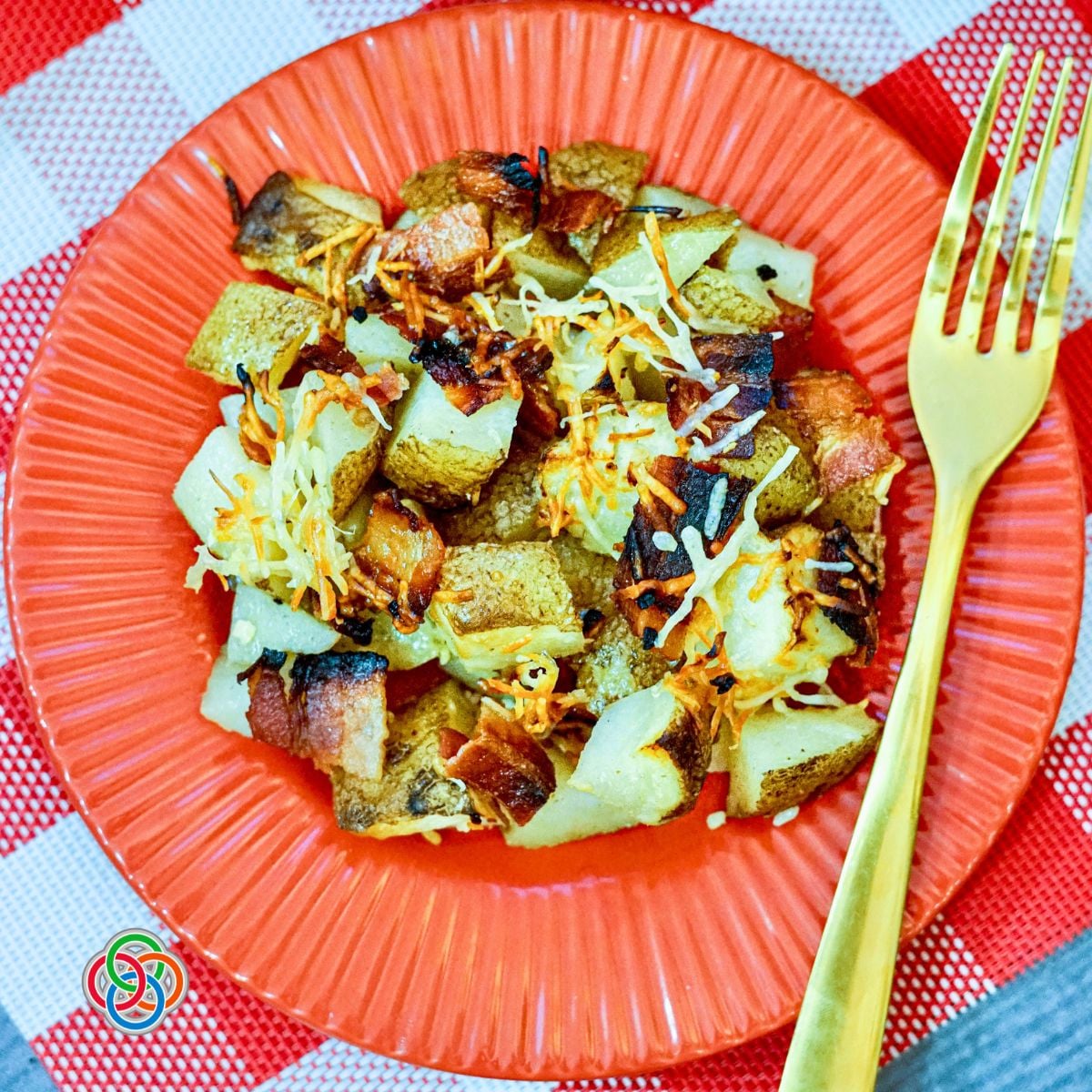 Bacon Parmesan Sheetpan Potatoes | Irish American Mom Roasted Bacon Parmesan Sheet Pan Potatoes with crispy bacon, garlic and golden Parmesan cheese served on a red plate with a gold fork.