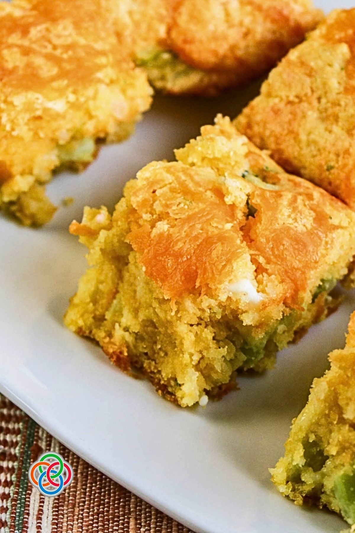 Broccoli Cheddar Cornbread Moist and Delicious | Irish American Mom Close-up of a moist square of broccoli cornbread topped with golden melted cheddar cheese, with pieces of broccoli visible throughout the tender cornbread.