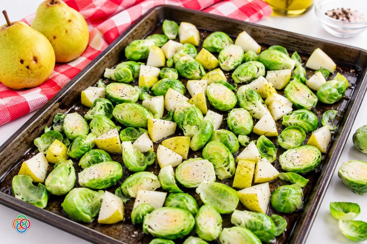 Brussels sprouts and pears on a sheetpan for roasting | Irish American Mom Halved Brussels sprouts and chunks of skin-on pear seasoned with salt and black pepper and spread in a single layer on a baking sheet ready for roasting.