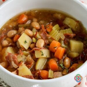 Close up of a bowl of ham bone and vegetable soup | Irish American Mom Close-up of homemade ham bone and vegetable soup with tender potatoes, carrots, celery, white beans and shredded ham in a savory broth.