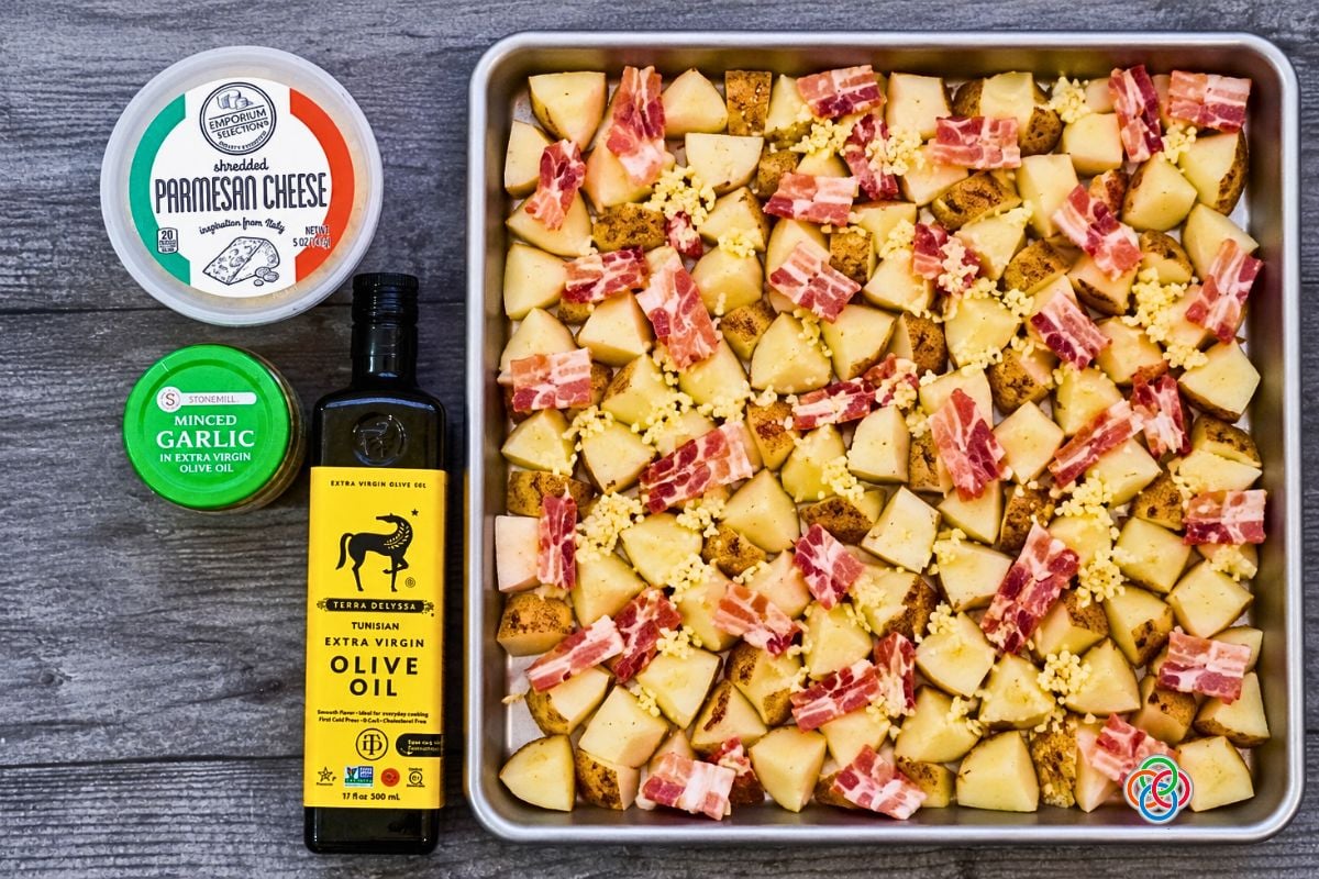 Cubed White Potatoes with bacon and garlic on a sheetpan for Bacon Parmesan Sheetp | Irish American Mom Cubed unpeeled white potatoes topped with chopped bacon and minced garlic on a sheet pan, ready for olive oil and Parmesan cheese before roasting.