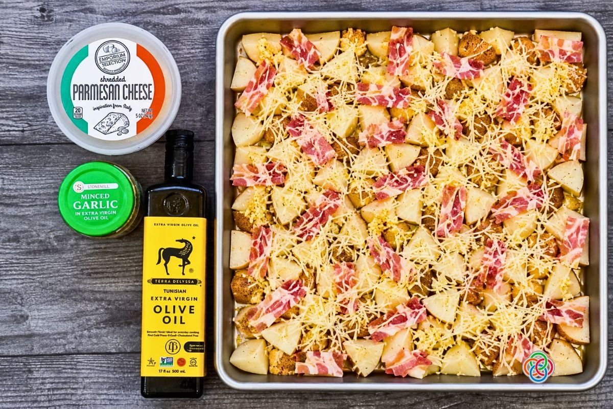 Cubed White Potatoes with parmesan shreds bacon and garlic on a sheetpan for Bacon | Irish American Mom Cubed white potatoes topped with chopped bacon, minced garlic and shredded Parmesan cheese on a sheet pan, ready to roast in the oven.