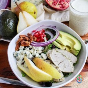 Fall Salad Pear and Turkey with Pomegranate Seeds and Gorgonzola | Irish American Mom Harvest pear salad with sliced turkey, fresh pears, avocado, pomegranate seeds, red onion, Gorgonzola cheese and honey-roasted pecans served in a white bowl with creamy dressing.