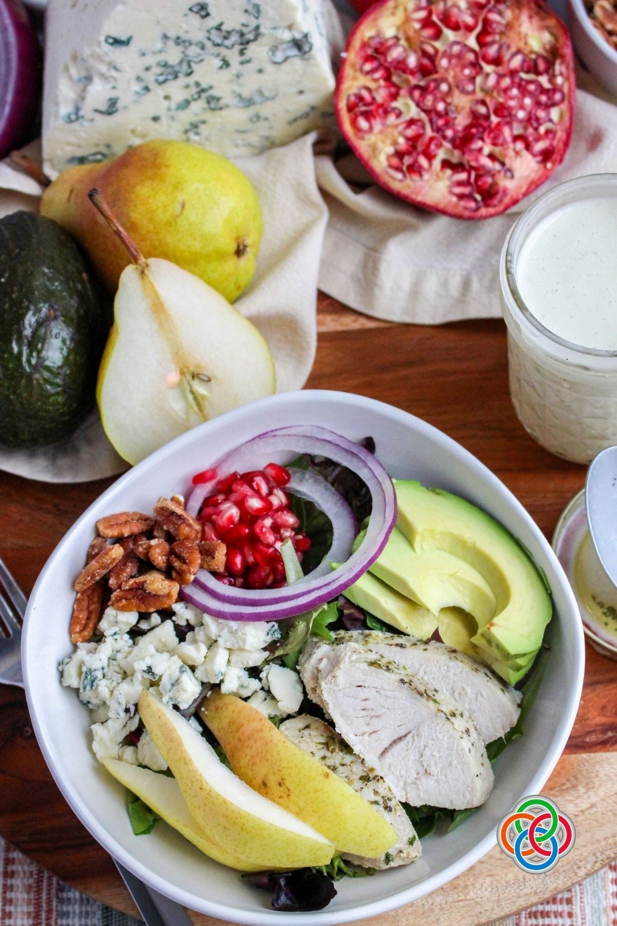 Fall or Harvest Pear and Pecan Salad | Irish American Mom Harvest pear salad with sliced turkey, fresh pears, avocado, pomegranate seeds, red onion, Gorgonzola cheese and honey-roasted pecans served in a white bowl with creamy Gorgonzola dressing.