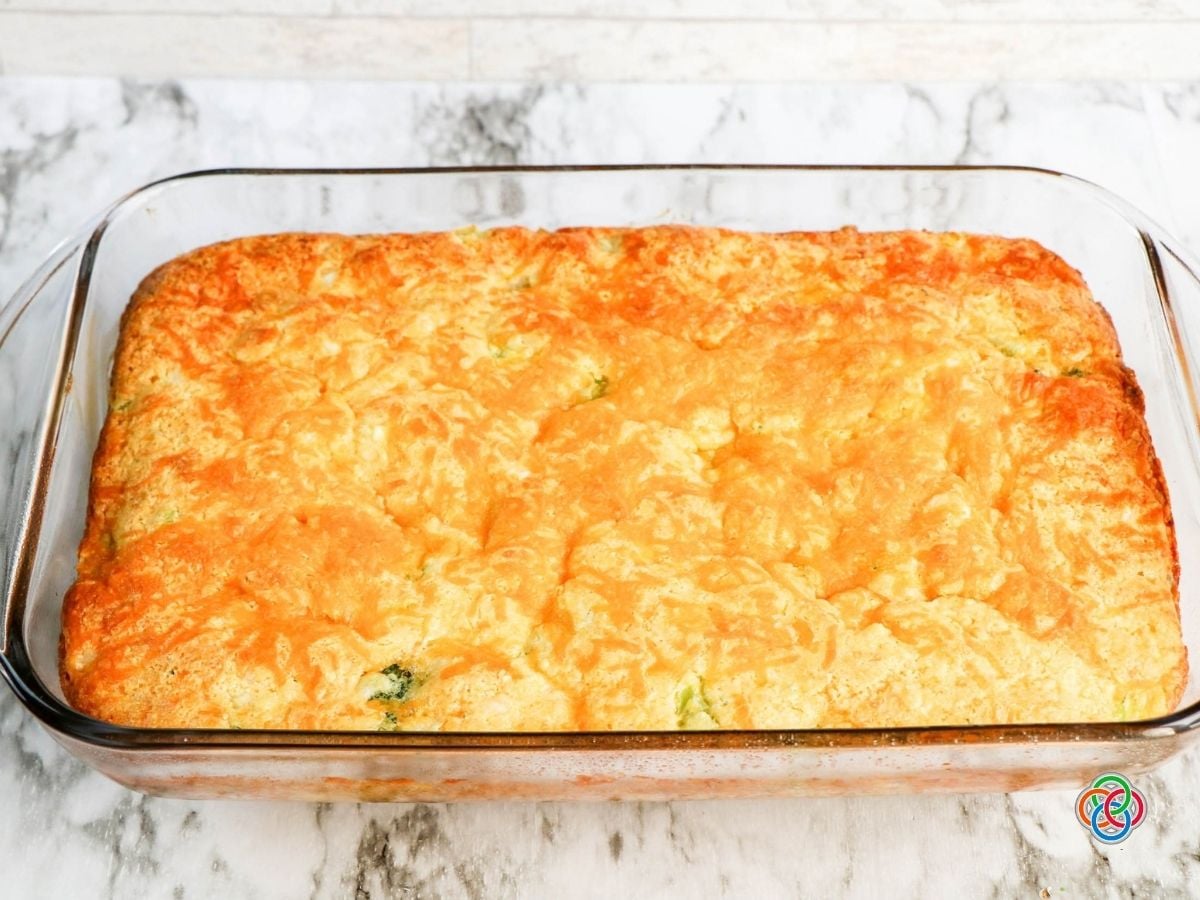 Freshly baked golden topped cheddar broccoli cornbread | Irish American Mom Freshly baked broccoli cheddar cornbread in a rectangular glass casserole dish with a puffed, golden-brown cheddar cheese topping.