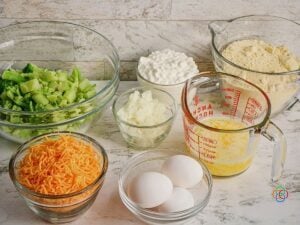 Ingredients for cheddar broccoli cornbread | Irish American Mom Ingredients for cheesy broccoli cornbread arranged in glass bowls, including chopped broccoli, shredded cheddar cheese, cottage cheese, chopped onion, eggs, melted butter and cornbread mix.