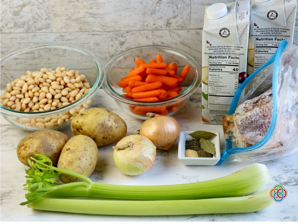 Ingredients for slow cooker ham bone soup | Irish American Mom Ingredients for slow cooker ham bone soup including a meaty ham bone, potatoes, carrots, celery, onions, white beans, chicken broth, bay leaves and dried seasonings.