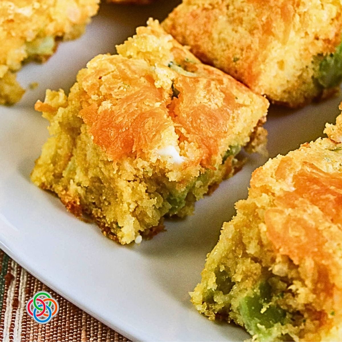 Moist cornbread with cheddar broccoli onion and cottage cheese | Irish American Mom Close-up of moist broccoli cheddar cornbread squares with pieces of broccoli and onion throughout and a golden layer of melted cheddar cheese on top.
