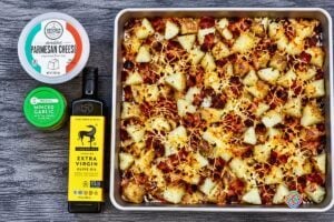 Roasted Bacon Parmesan Sheetpan Potatoes Just Out of the Oven | Irish American Mom Freshly roasted Bacon Parmesan Sheet Pan Potatoes with golden potato chunks, crispy bacon, garlic and browned melted Parmesan cheese on a baking sheet.
