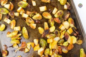 Roasted Brussels sprouts and pears crisped in the oven | Irish American Mom Golden roasted Brussels sprouts and chunks of pear with caramelized, crispy edges spread across a baking sheet after roasting in the oven.