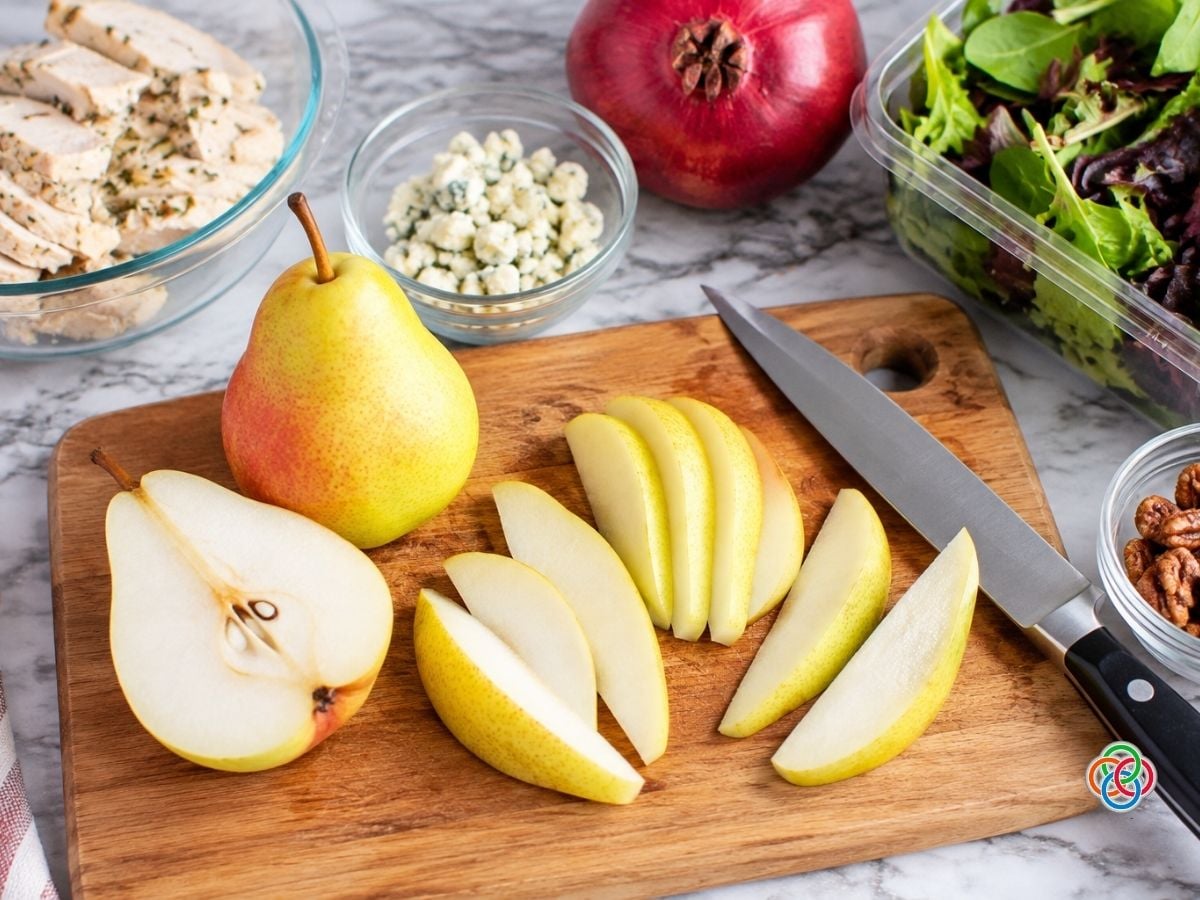 Slicing pears for a turkey and pear harvest salad | Irish American Mom Fresh Bartlett pears being prepared for a harvest salad, with whole, halved and sliced pears on a wooden cutting board surrounded by turkey, Gorgonzola cheese, mixed greens and pecans.