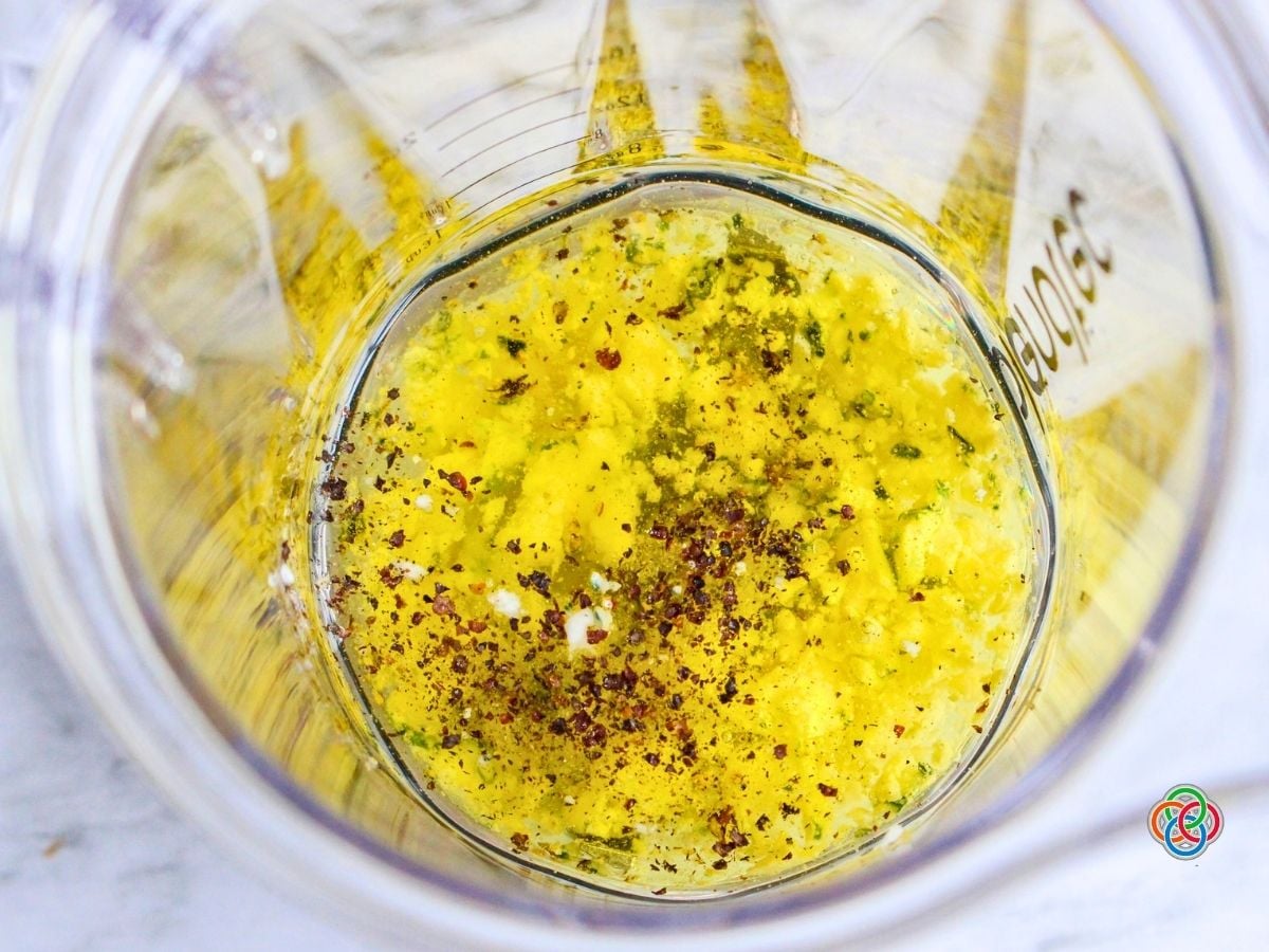 Using a Blender to make a Gorgonzola Salad Dressing | Irish American Mom Overhead view of olive oil, crumbled Gorgonzola cheese, vinegar, lemon juice and black pepper combined in a blender before blending into a creamy Gorgonzola salad dressing.