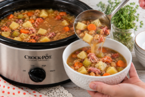 ladling soup into bowls | Irish American Mom Pouring ham and vegetable soup into a bowl using a ladle beside a slow cooker of cooked soup.