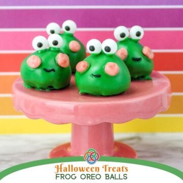 Three adorable green frog Oreo truffles with white candy eyes, pink candy cheeks, and black icing smiles displayed on a pink pedestal cake stand against a colorful pink, purple, and orange striped background over a text banner.
