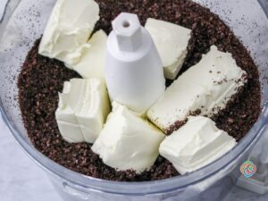 Oreo cookies crumbs and cream cheese in a food processor | Irish American Mom Cream cheese and crumbled chocolate cookies in a food processor
