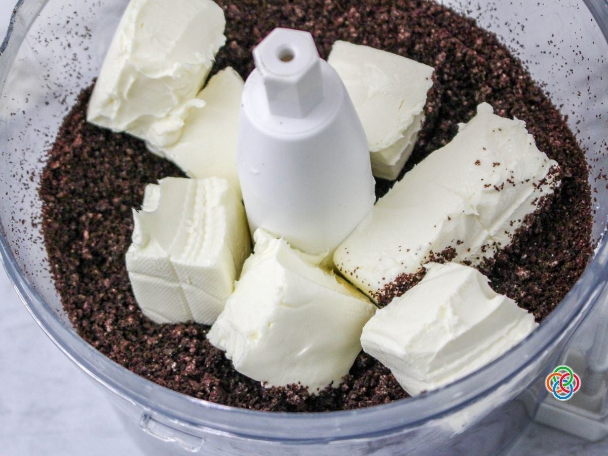 Oreo cookies crumbs and cream cheese in a food processor | Irish American Mom Cream cheese and crumbled chocolate cookies in a food processor